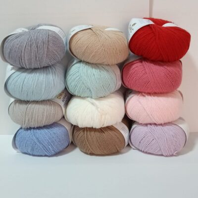 Pila de doce ovillos lana colores etiqueta dmc merino essentiel 3 soft light pure wool blend